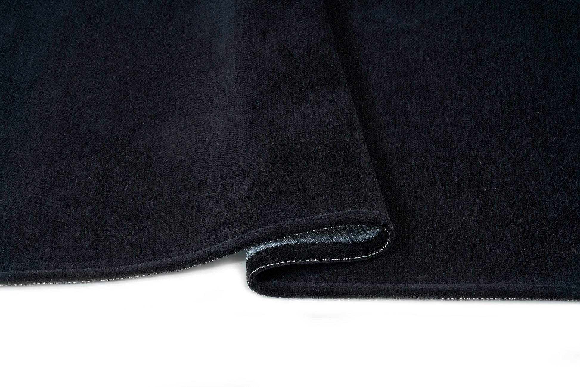 Tapis noir, densité élevée, moelleux, confort visuel. Forme rectangulaire. Ambiance feutrée