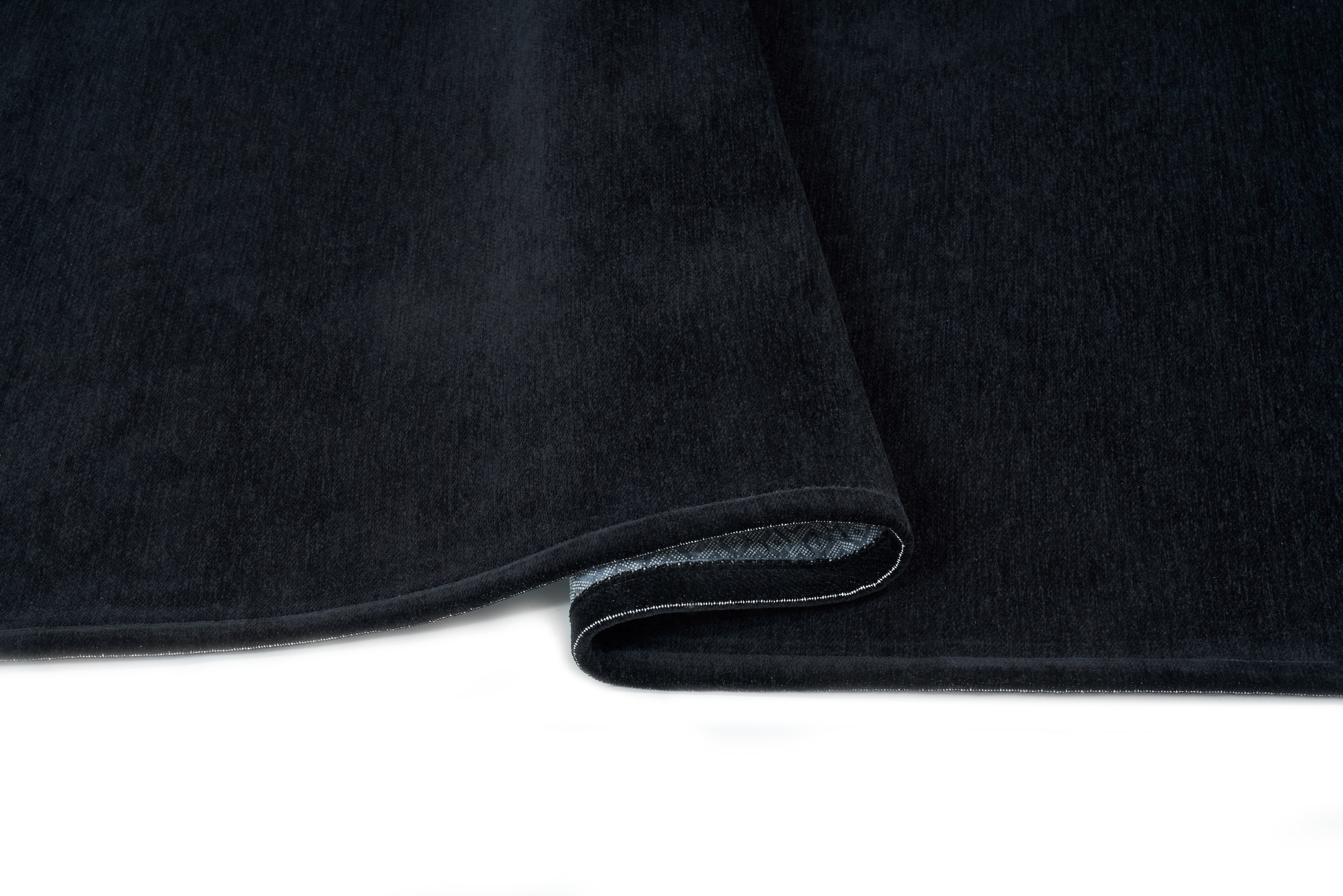 Tapis noir, densité élevée, moelleux, confort visuel. Forme rectangulaire. Ambiance feutrée