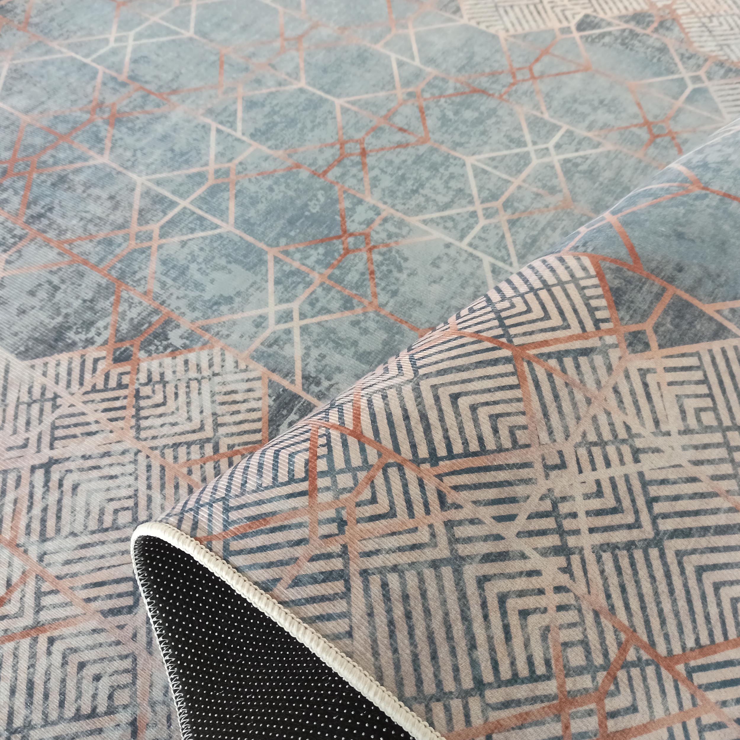 Tapis à motifs géométriques: polygones cuivrés sur fond bleu-gris, et entrelacs sombres sur un fond beige clair
