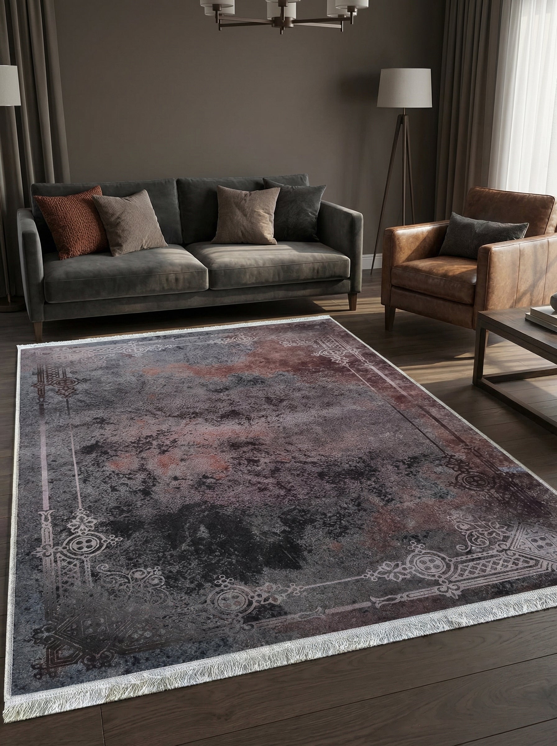 Grand tapis rectangulaire aux teintes sombres gris-anthracite et rouille, motifs floraux stylisés clairs en bordure et franges, dans un salon