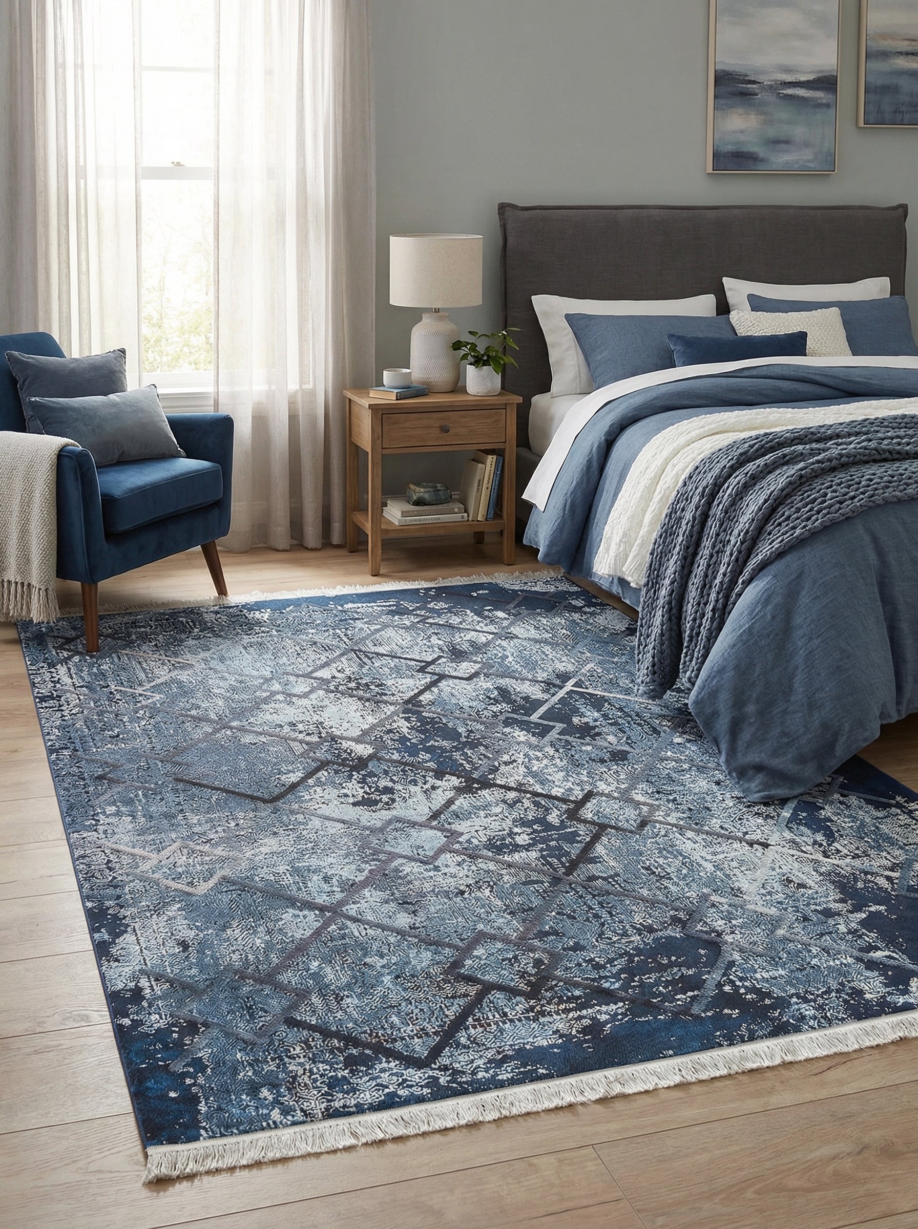 Tapis rectangulaire bleu marine et gris aux motifs abstraits géométriques superposés, effet délavé, avec franges, dans une chambre