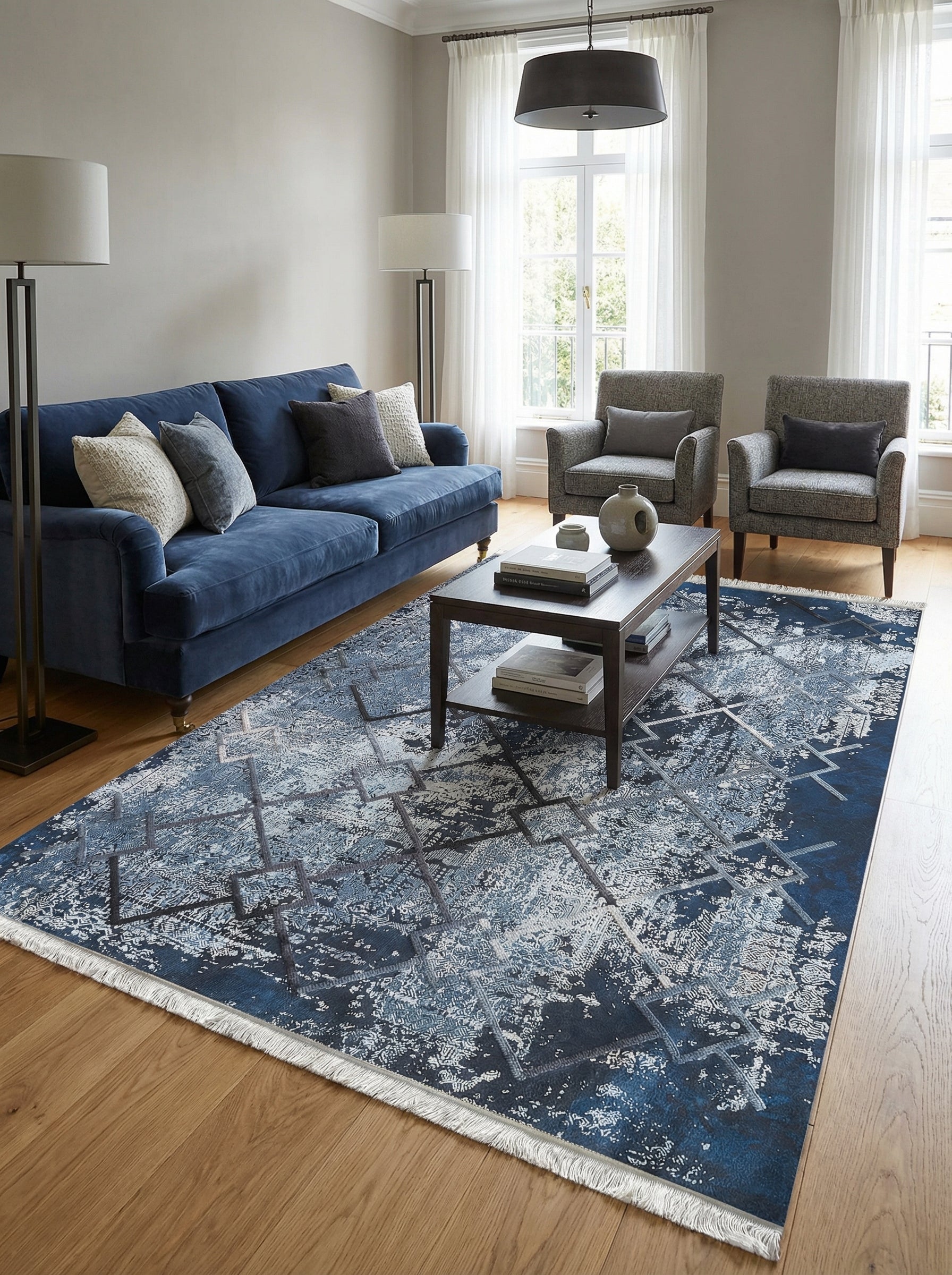 Tapis rectangulaire bleu marine et gris clair, aux motifs abstraits et délavés avec franges, posé dans un salon