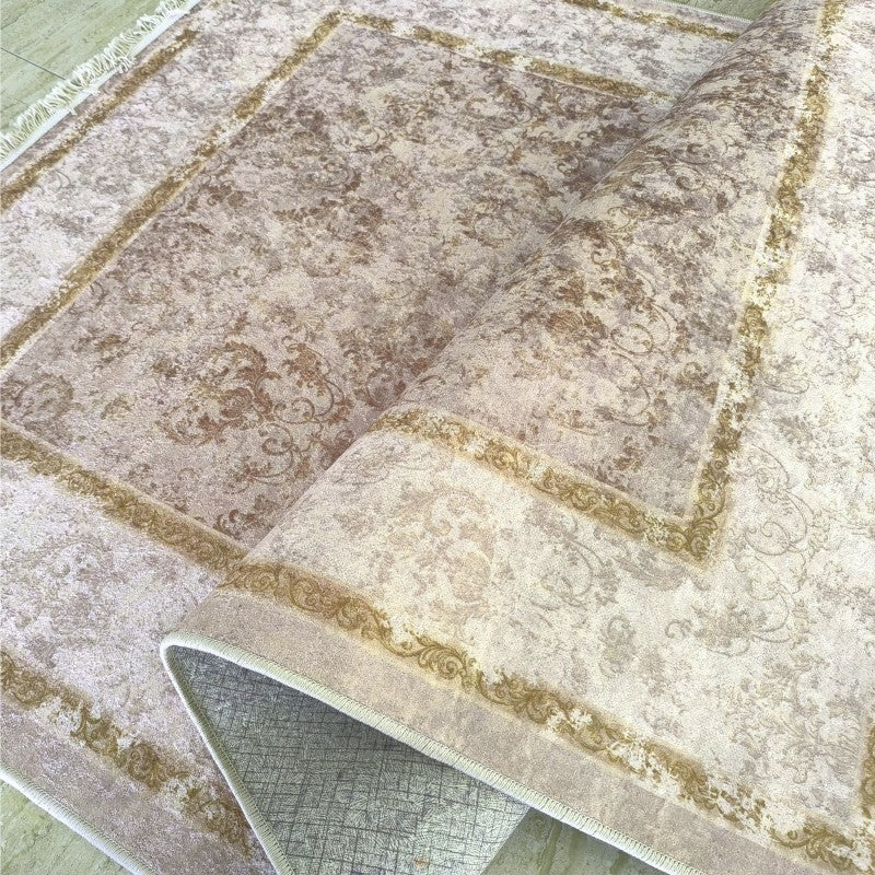 Tapis beige et crème à motifs classiques floraux marron doré, partiellement enroulé montrant sa texture douce