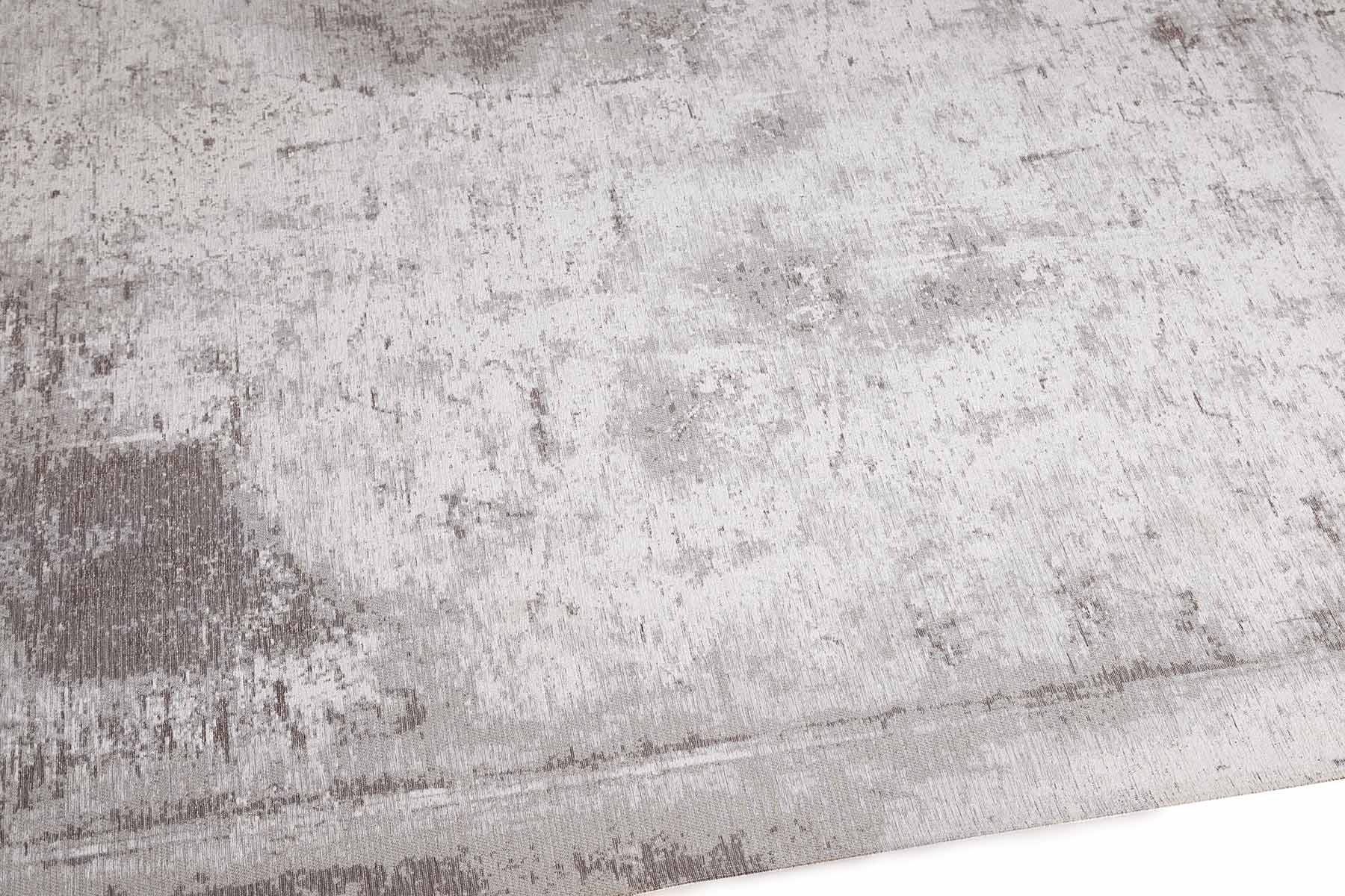 Tapis rectangulaire gris, tissage texturé avec relief. Aspect tactile doux et irrégulier. Ambiance feutrée