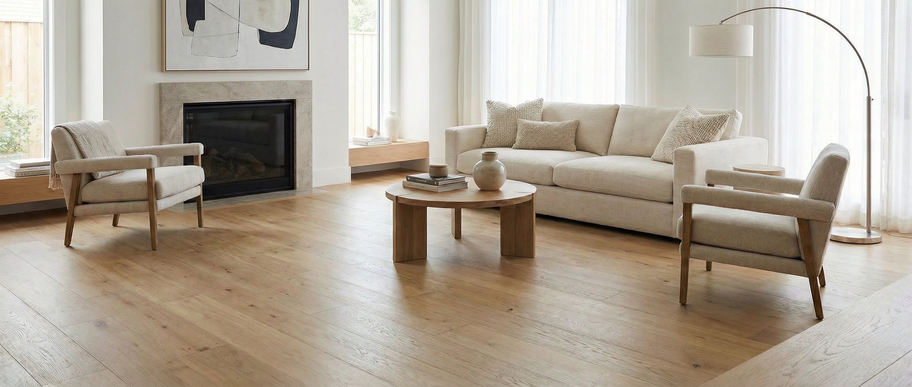 Pièce lumineuse avec parquet clair. Canapé beige, fauteuils et table basse en bois. Espace vide pour un tapis