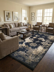 Grand tapis rectangulaire bleu nuit et crème avec des motifs floraux et médaillons au style vieilli, posé dans un salon