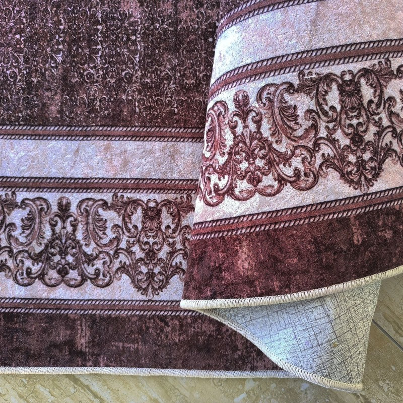 Tapis aux riches motifs baroques bordeaux et beige, avec des bordures texturées, partiellement enroulé