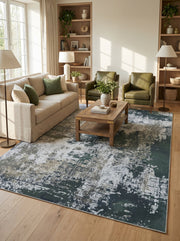 Tapis rectangulaire abstrait aux motifs irréguliers verts foncés, gris clairs et beiges sur un sol en bois clair dans un salon