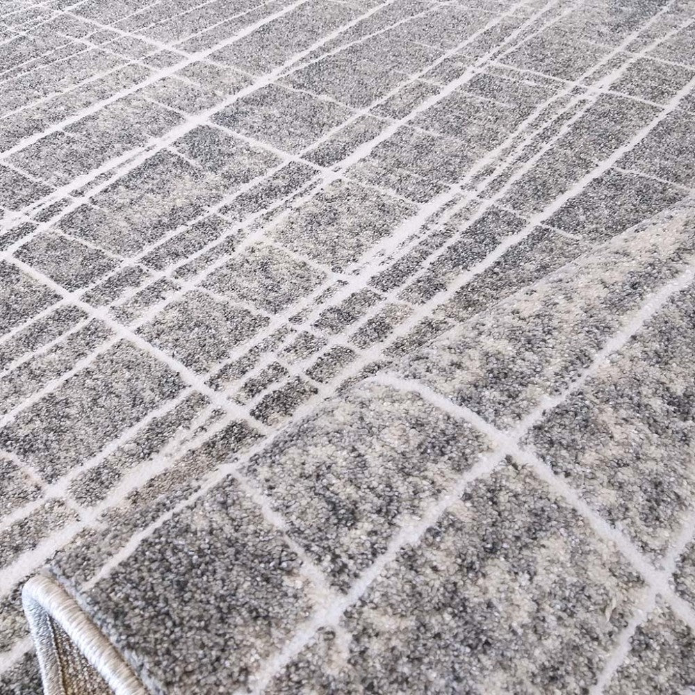 Tapis moelleux gris chiné et blanc avec un motif de grille aux lignes blanches texturées et irrégulières