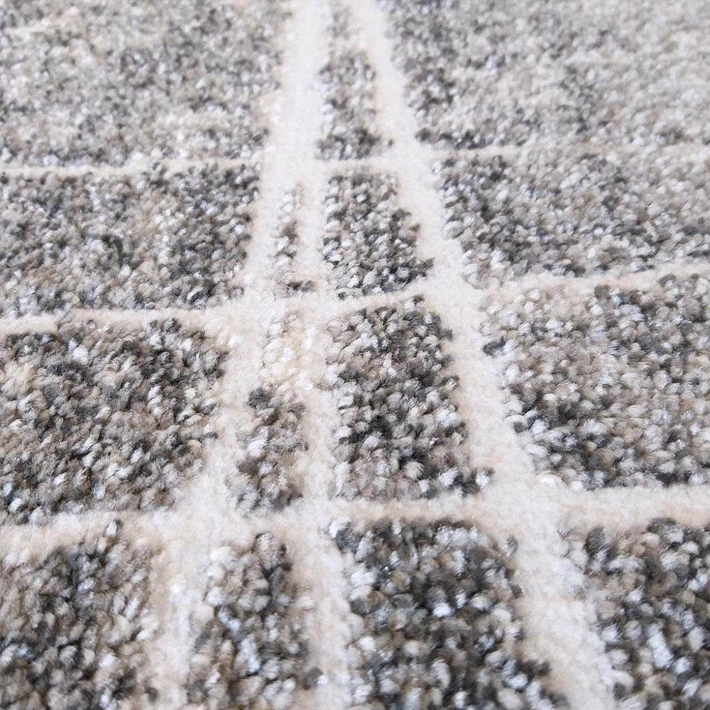 Tapis à poils longs avec un motif quadrillé de carrés gris, noirs et blancs, séparés par des lignes claires