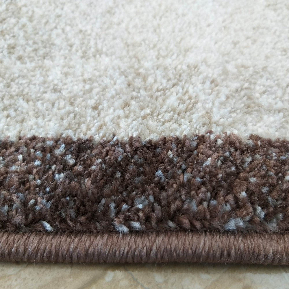 Tapis à poils longs aux teintes de beige clair et marron foncé moucheté de blanc, avec une bordure unie marron