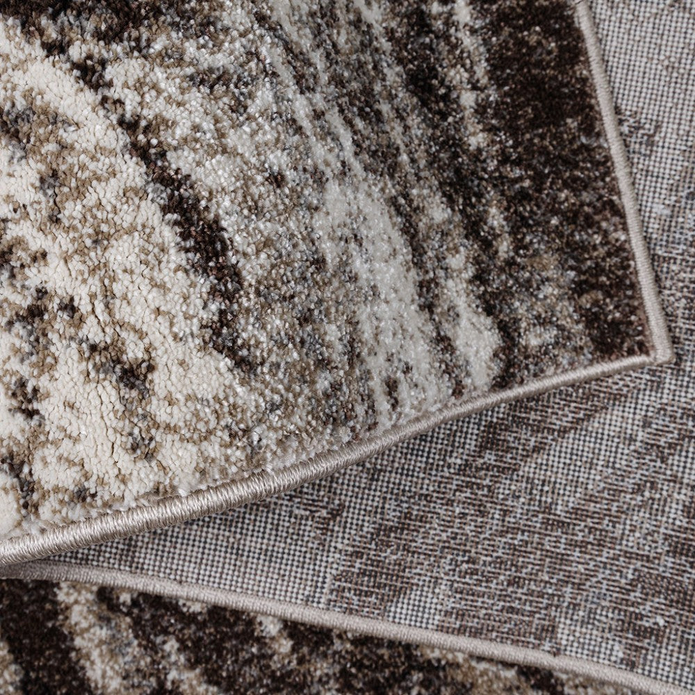 Tapis à l'aspect moucheté beige, marron et gris foncé, avec un bord ourlé et la trame tissée de son envers visible