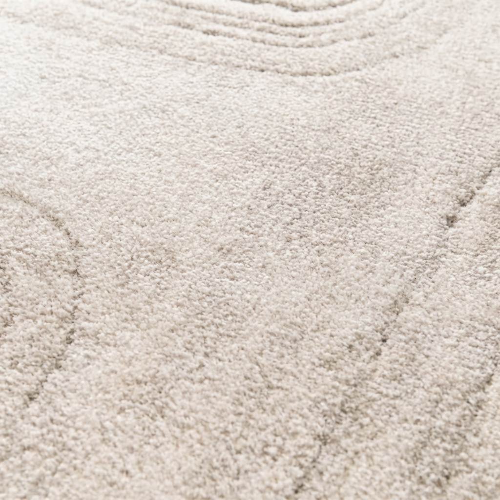 Tapis doux de couleur beige clair, présentant des motifs de lignes ondulées subtiles et grisées en relief