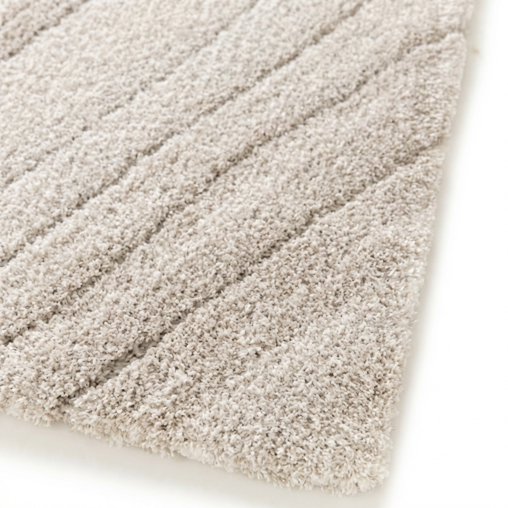 Tapis moelleux de couleur écru ou blanc cassé, présentant un motif de rayures diagonales en relief formées par les fibres