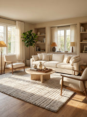 Tapis rectangulaire beige clair à poils longs avec des motifs ondulés en relief, posé sur un plancher en bois dans un salon lumineux