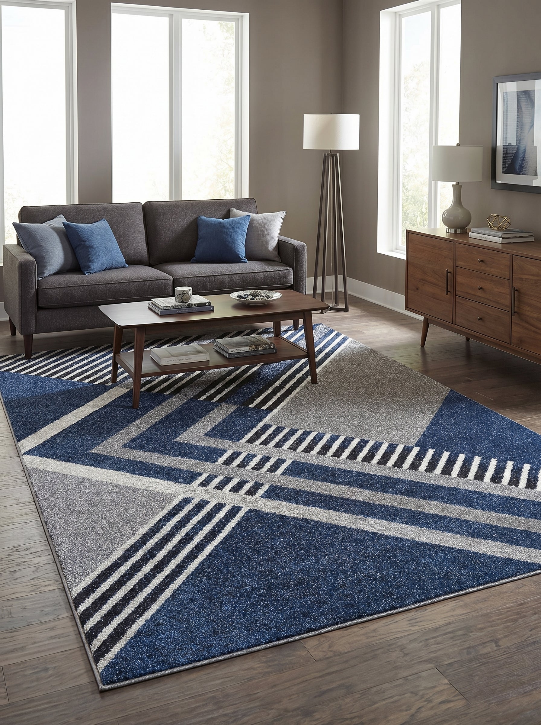 Tapis rectangulaire à motifs géométriques bleus, gris clairs, gris foncés et blancs sur un parquet en bois dans un salon