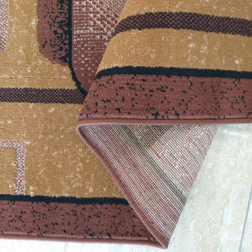 Tapis enroulé présentant un motif géométrique abstrait aux tons de beige, marron, bordeaux et noir. On voit le dessus velouté et le dessous tissé