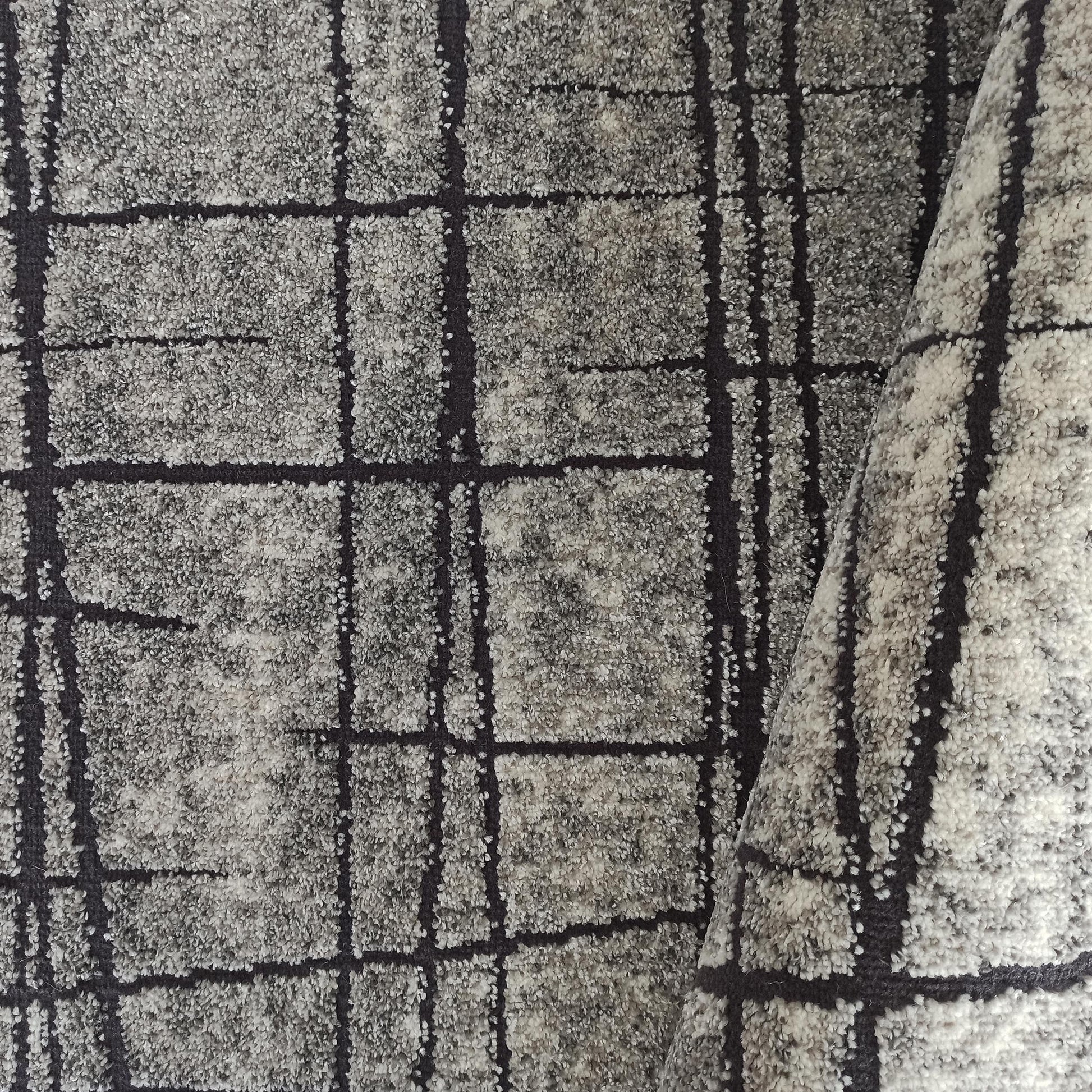 Tapis à texture mouchetée gris clair et gris foncé, avec un motif de lignes sombres irrégulières
