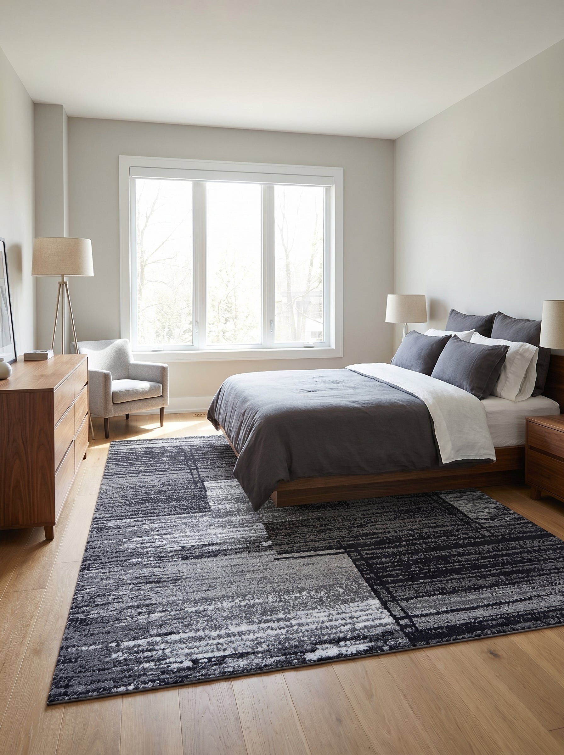Tapis rectangulaire aux motifs abstraits gris foncé, gris clair et blancs, avec une texture striée, posé dans une chambre moderne