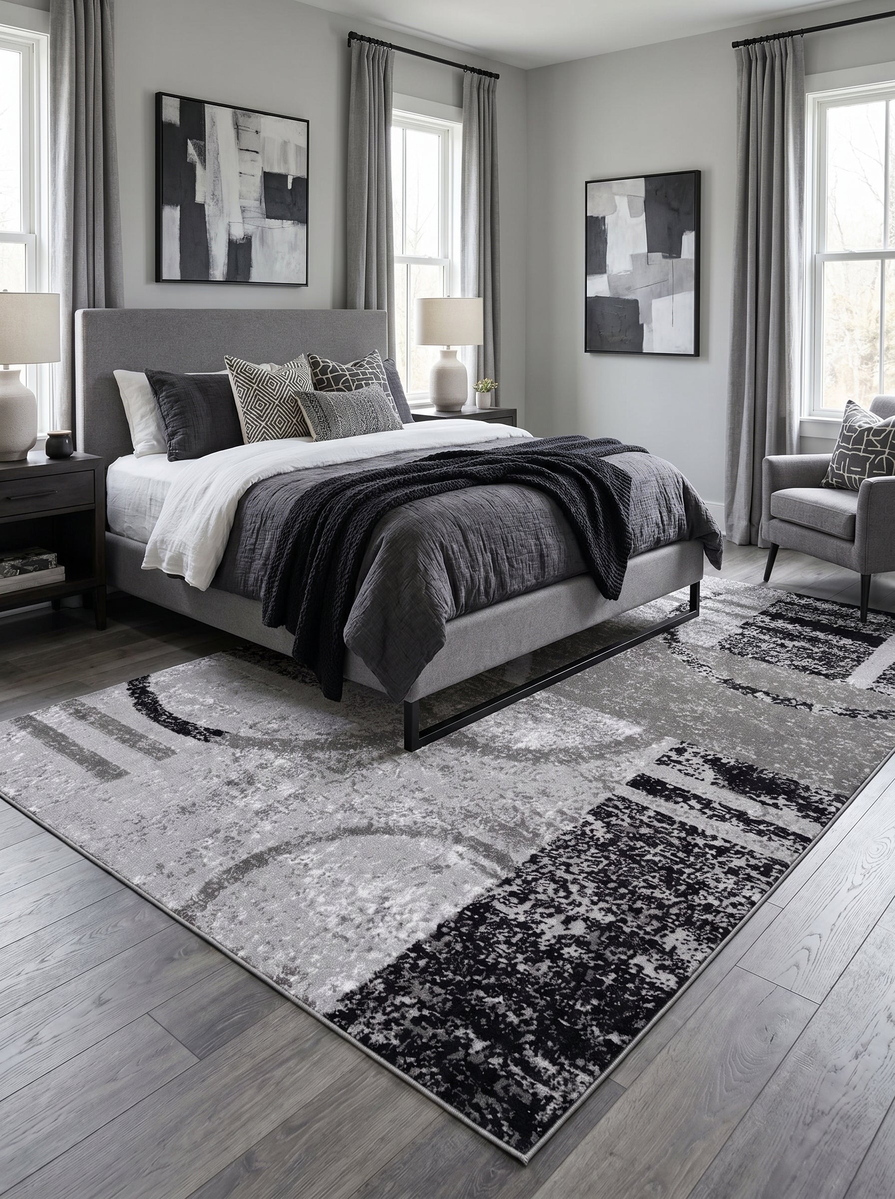 Tapis rectangulaire à motifs abstraits gris clair, foncé et noirs, texturé, sur sol en bois gris en chambre moderne