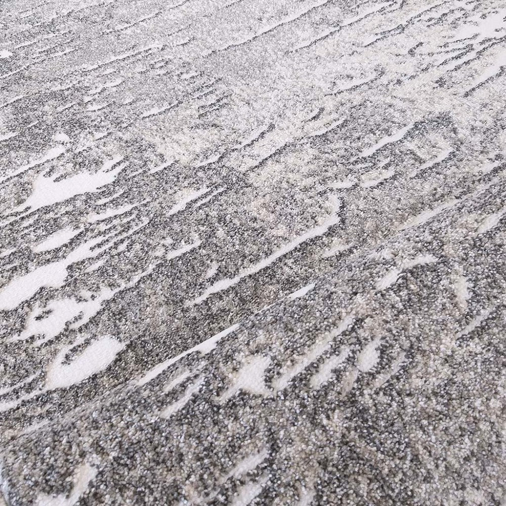 Tapis texturé aux motifs abstraits gris foncé et gris clair sur fond blanc cassé, ressemblant à des rayures organiques