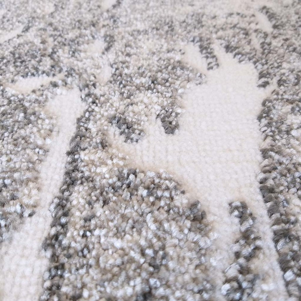 Gros plan sur un tapis moelleux à motifs abstraits clairs et foncés, mêlant du blanc cassé et des tons de gris moucheté
