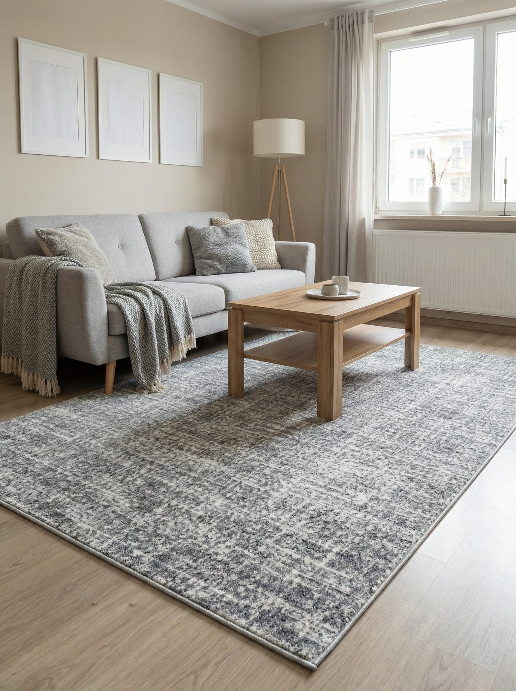 Tapis rectangulaire gris et blanc aux motifs abstraits et texturés, posé sur un parquet dans un salon moderne et lumineux