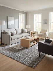 Tapis rectangulaire gris et blanc aux motifs géométriques abstraits posé sur un parquet clair dans un salon