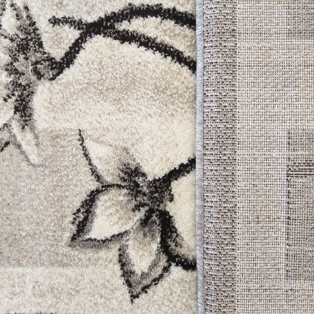 Tapis moelleux crème et gris clair à motifs floraux foncés, avec son revers tissé beige quadrillé apparent