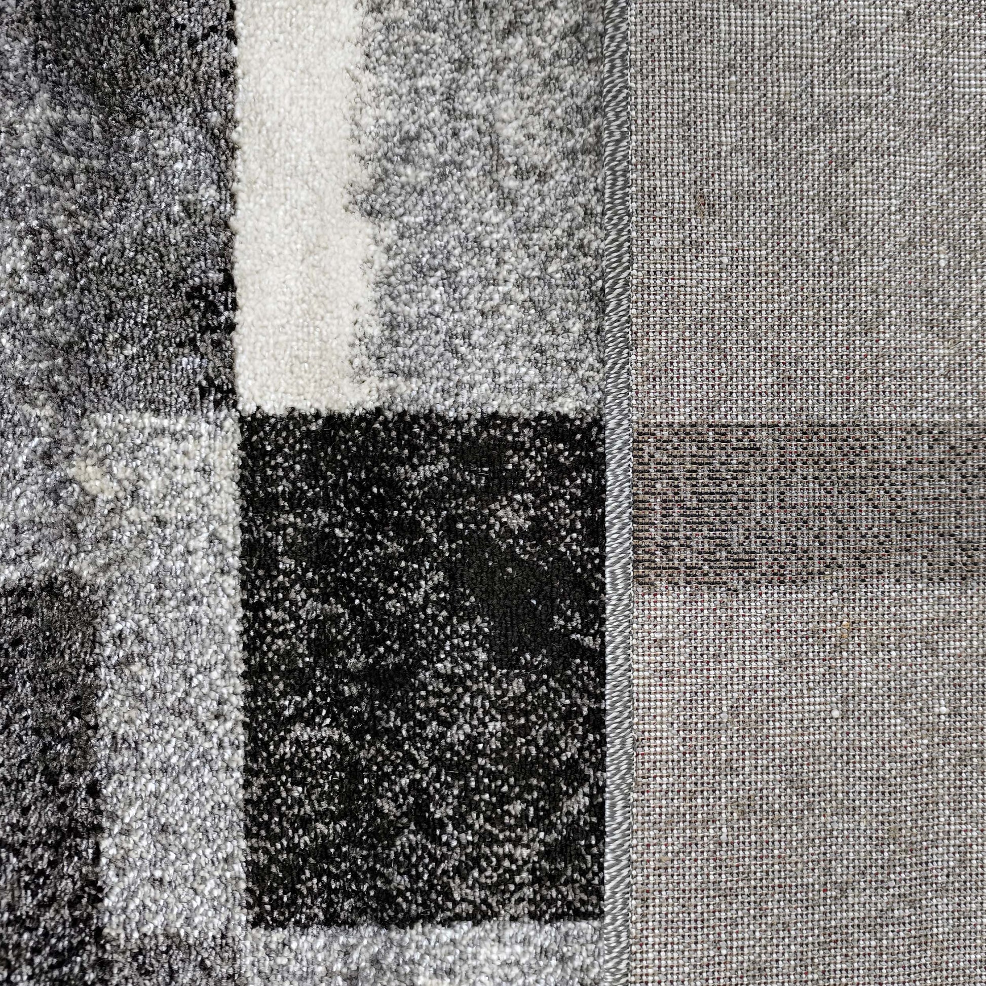 Tapis à poils longs à motif de grands carreaux gris, blancs et noirs, avec une section latérale en tissage fin beige