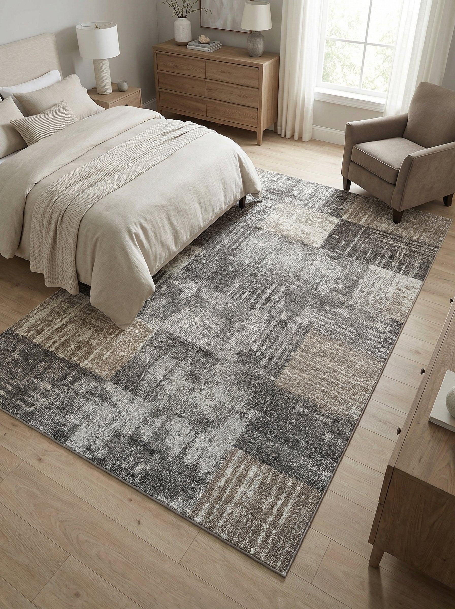 Tapis rectangulaire gris et beige avec un motif abstrait de blocs texturés, posé sur un plancher en bois clair dans une chambre
