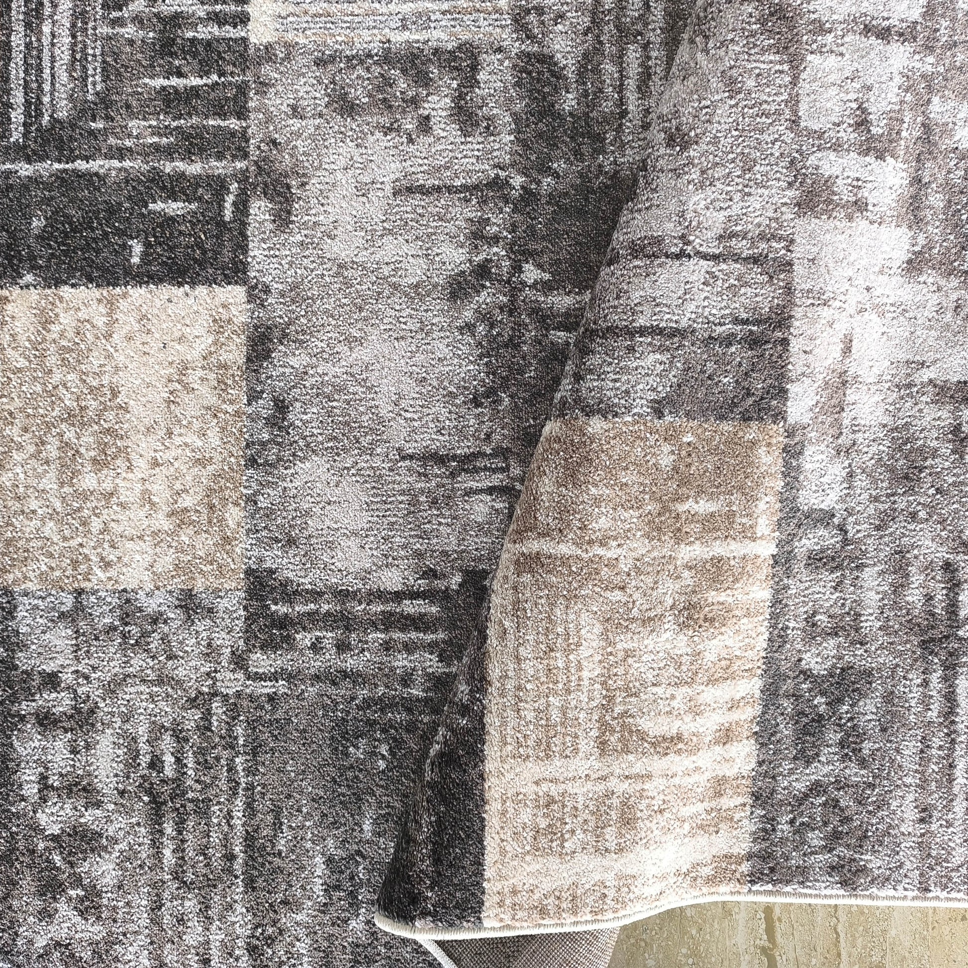 Tapis à poils longs et motifs fragmentés gris anthracite, gris clair et beige, légèrement plié