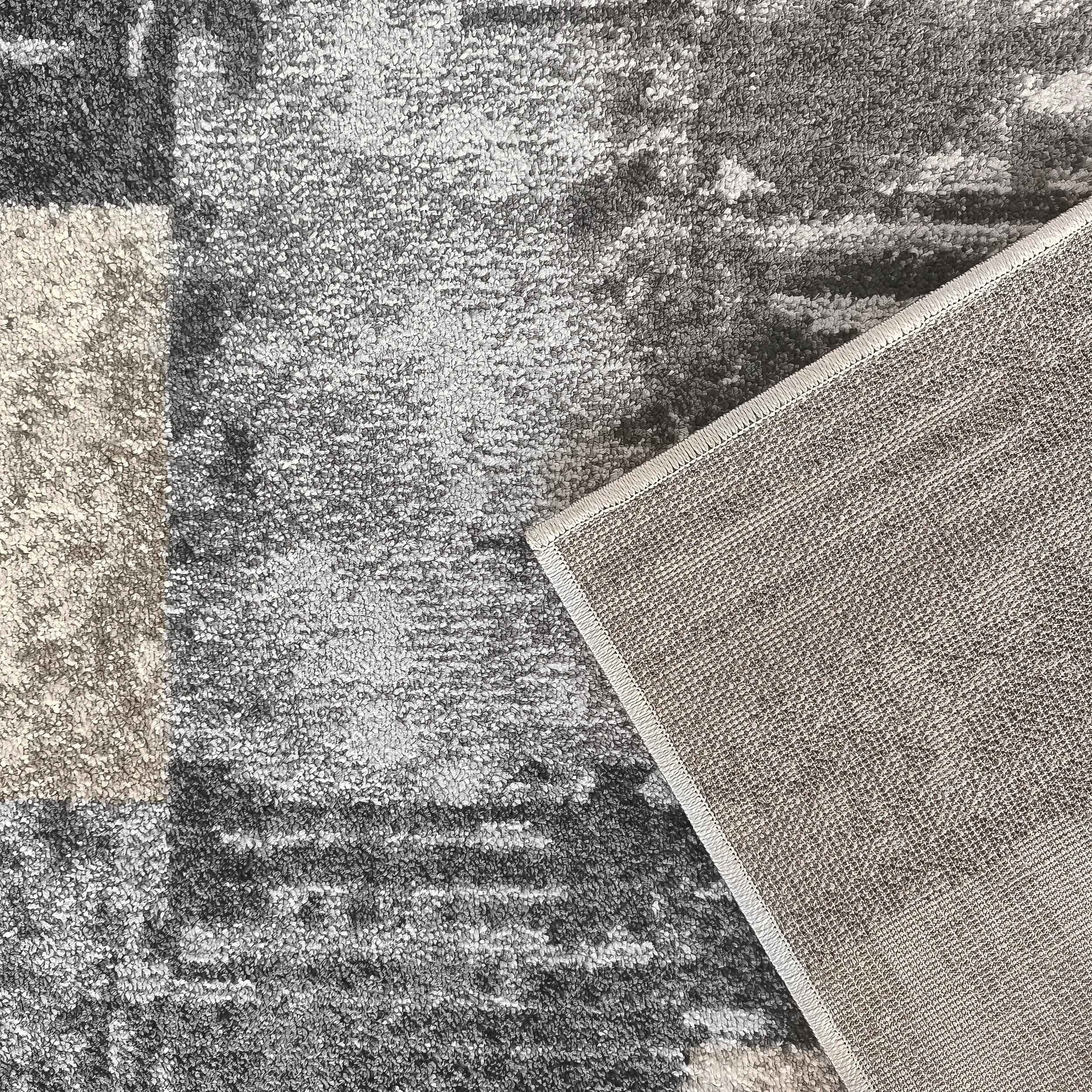 Tapis texturé aux motifs abstraits gris et beige, avec son envers tissé clair apparent