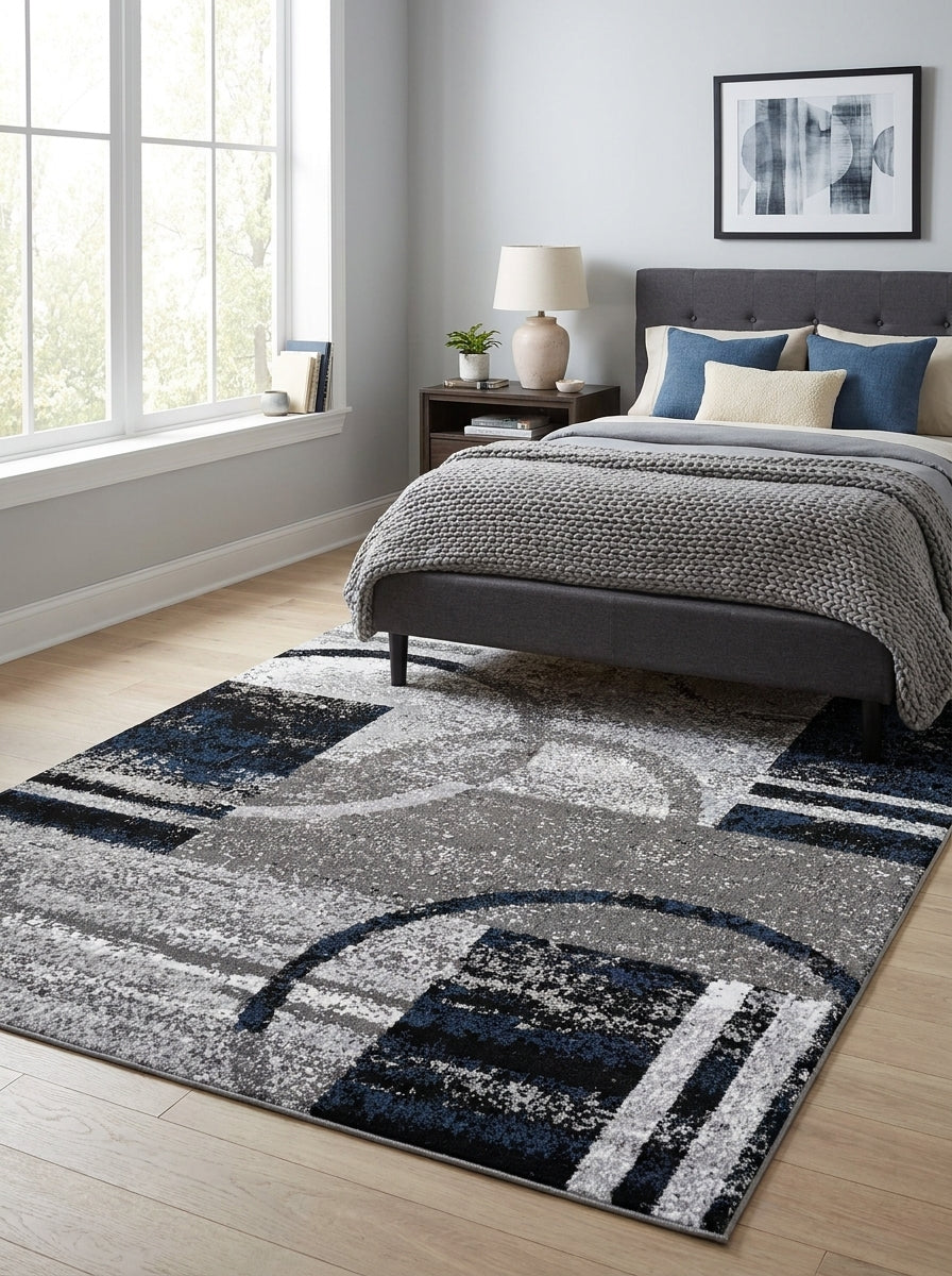 Tapis aux motifs géométriques abstraits texturés gris, blancs et bleu marine, dans une chambre