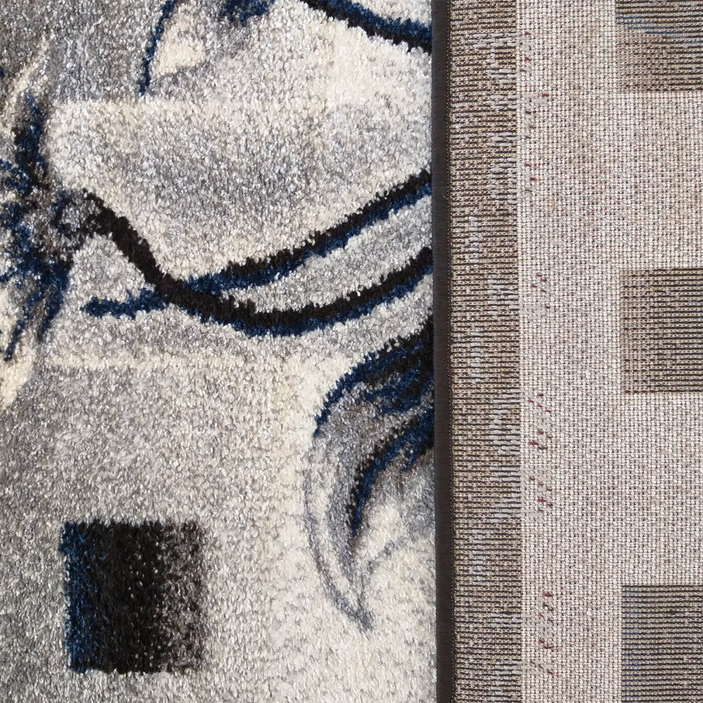 Tapis à poils épais gris, blanc, bleu marine et noir, aux motifs abstraits. L'envers du tapis est beige à motifs quadrillés