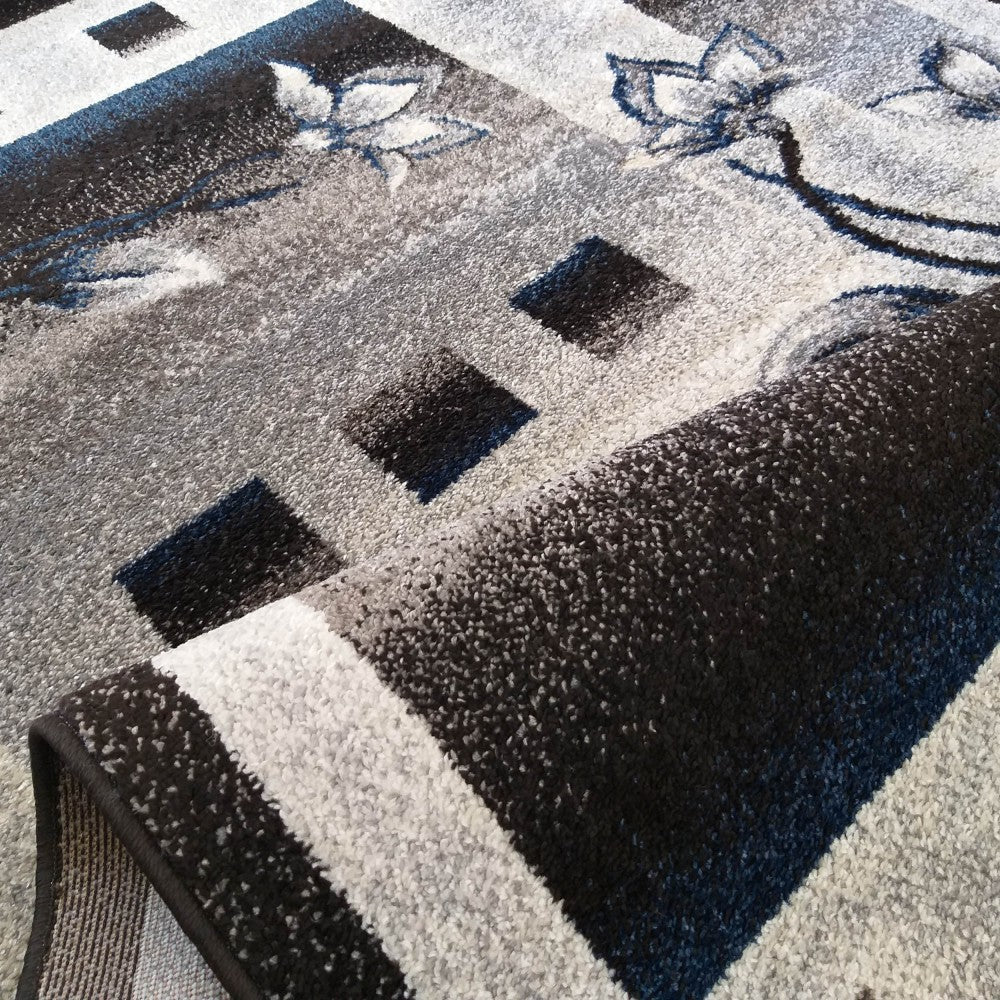 Tapis roulé à la texture courte, majoritairement gris, noir et blanc, orné de motifs géométriques et floraux bleus