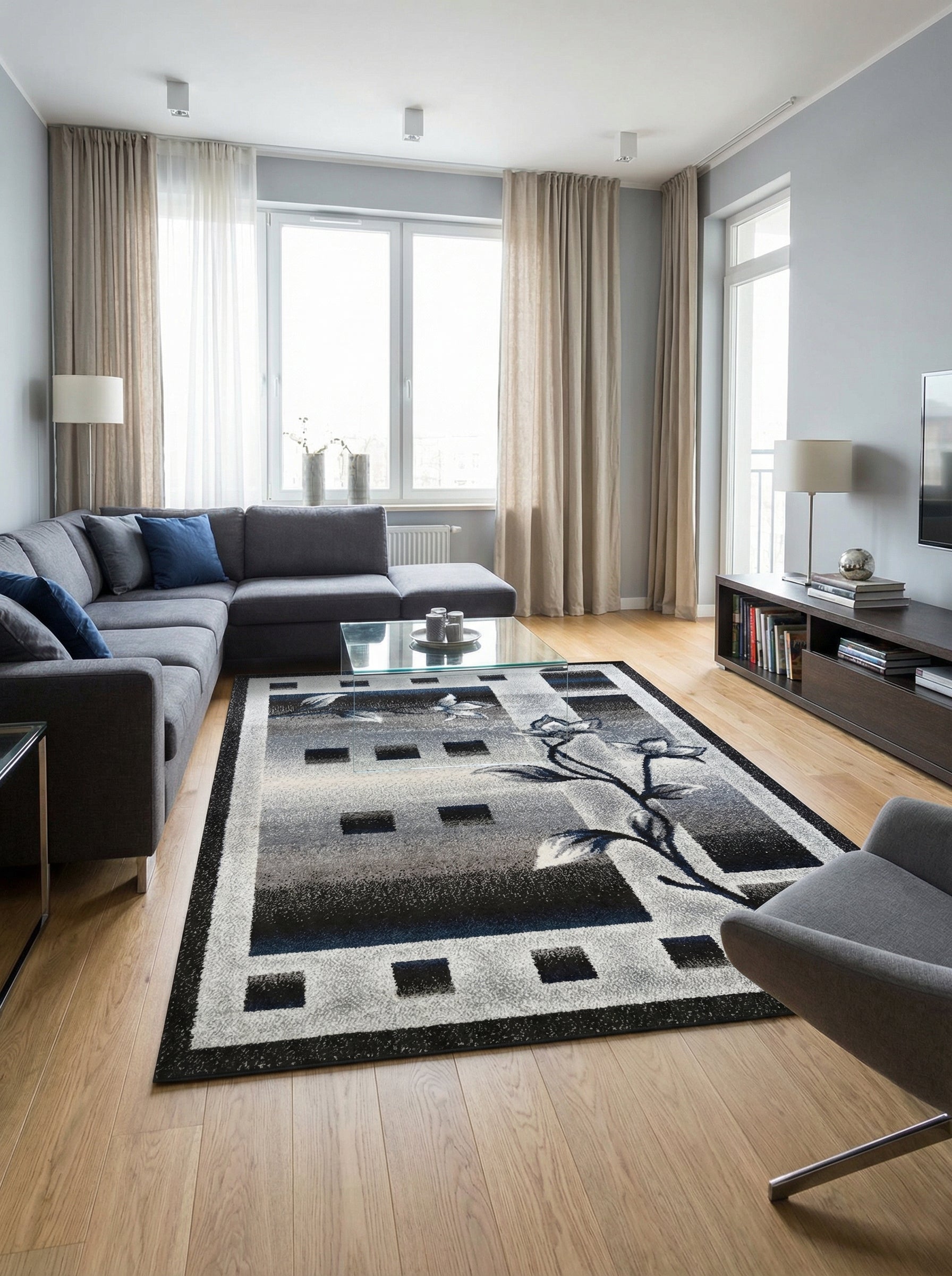 Tapis rectangulaire à motifs géométriques et floraux en dégradés de gris, noir et blanc, avec des touches de bleu, dans un salon