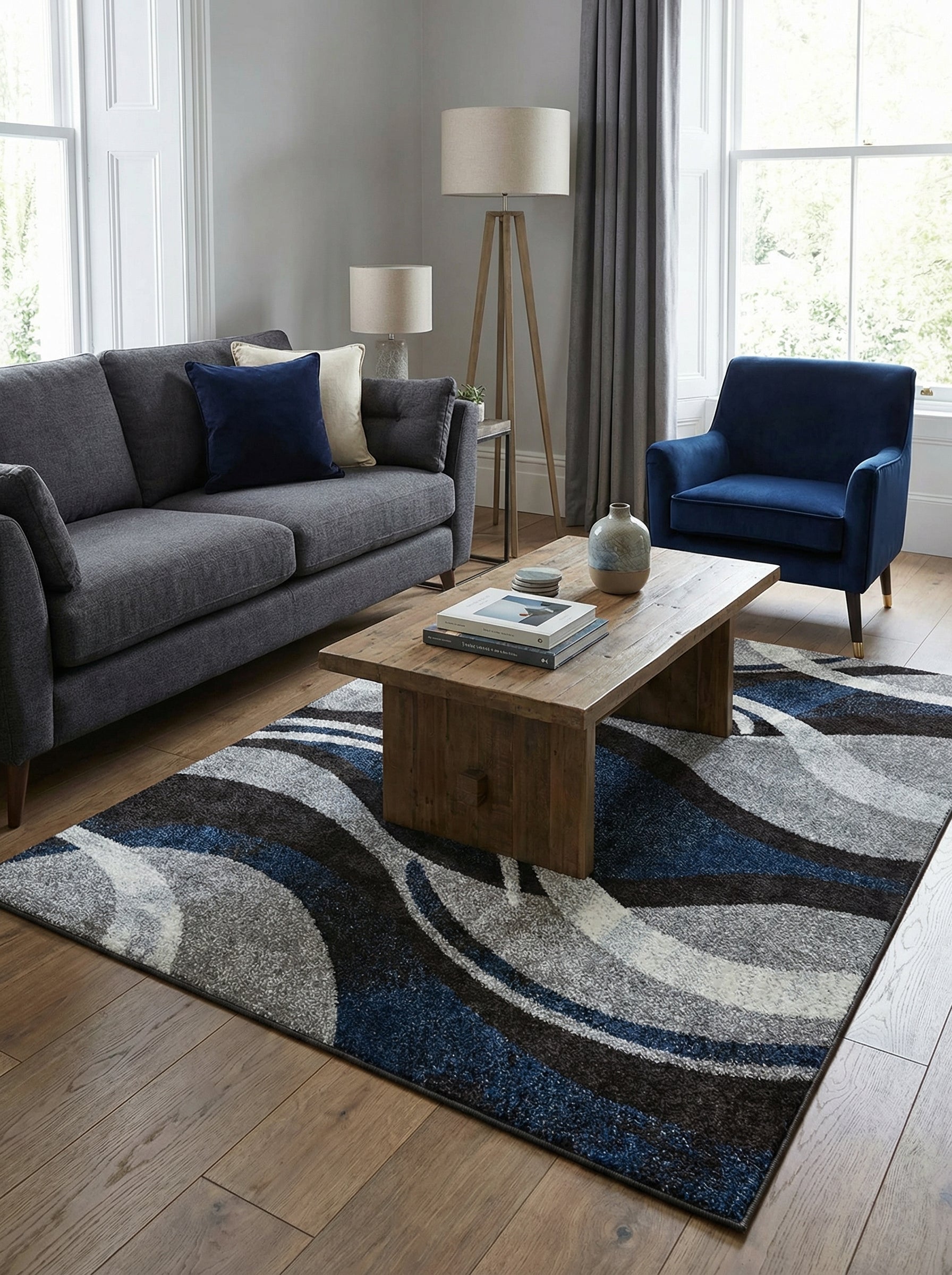 Tapis rectangulaire à motifs abstraits de vagues bleues, grises, noires et blanches, posé sur un parquet dans un salon