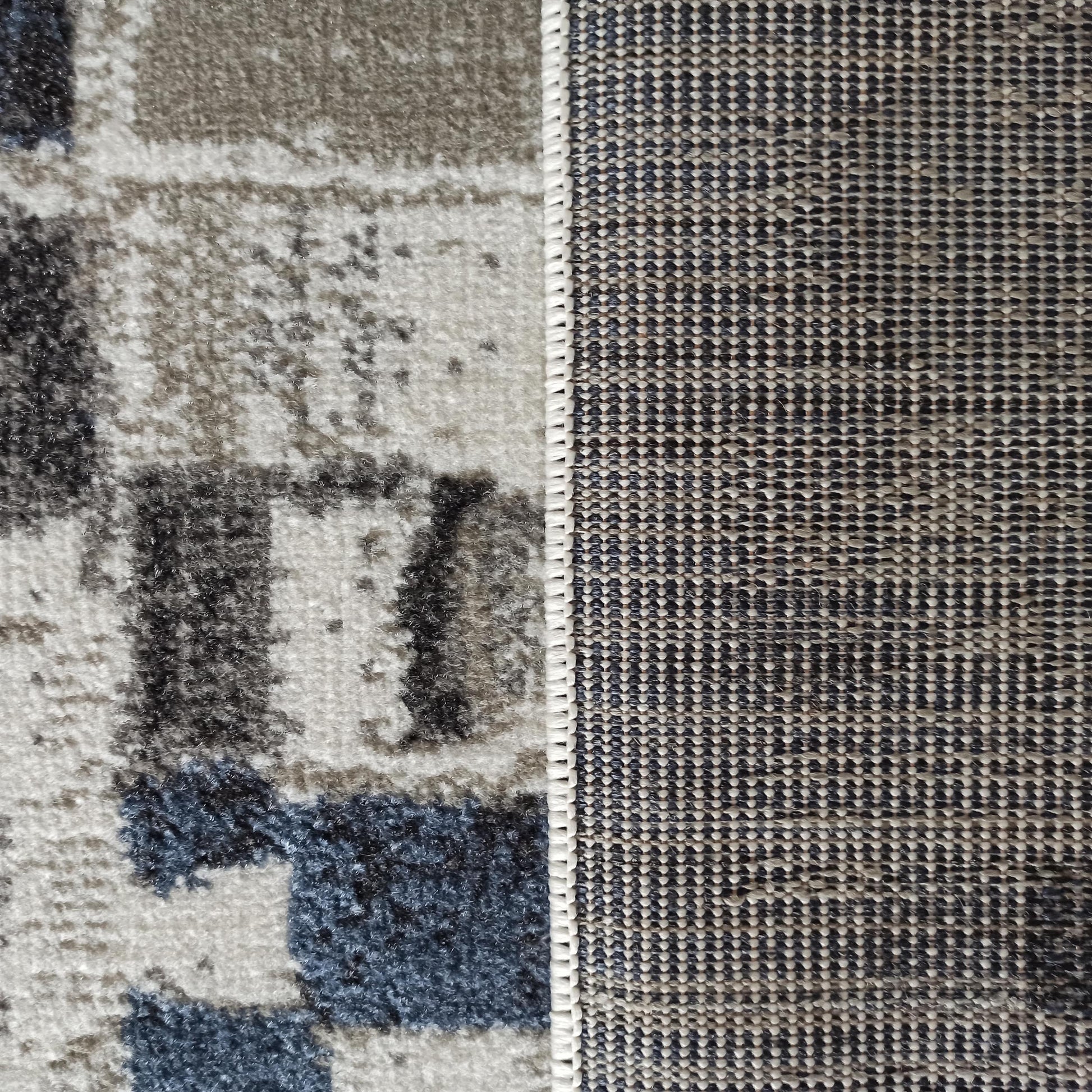 Gros plan d'un tapis aux motifs abstraits gris, blancs et bleus sur le dessus, et un envers en tissage serré