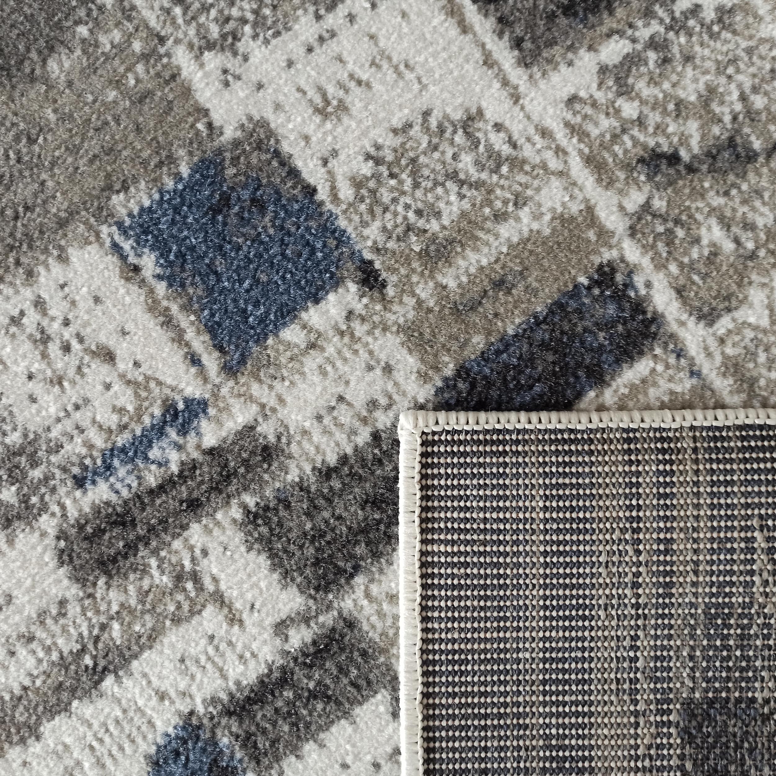 Tapis à motifs irréguliers blancs, gris et bleus à texture douce, montrant son envers tissé quadrillé
