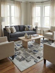 Tapis rectangulaire à motifs abstraits de carrés gris, bleu marine et blanc cassé, texture tissée, dans un salon