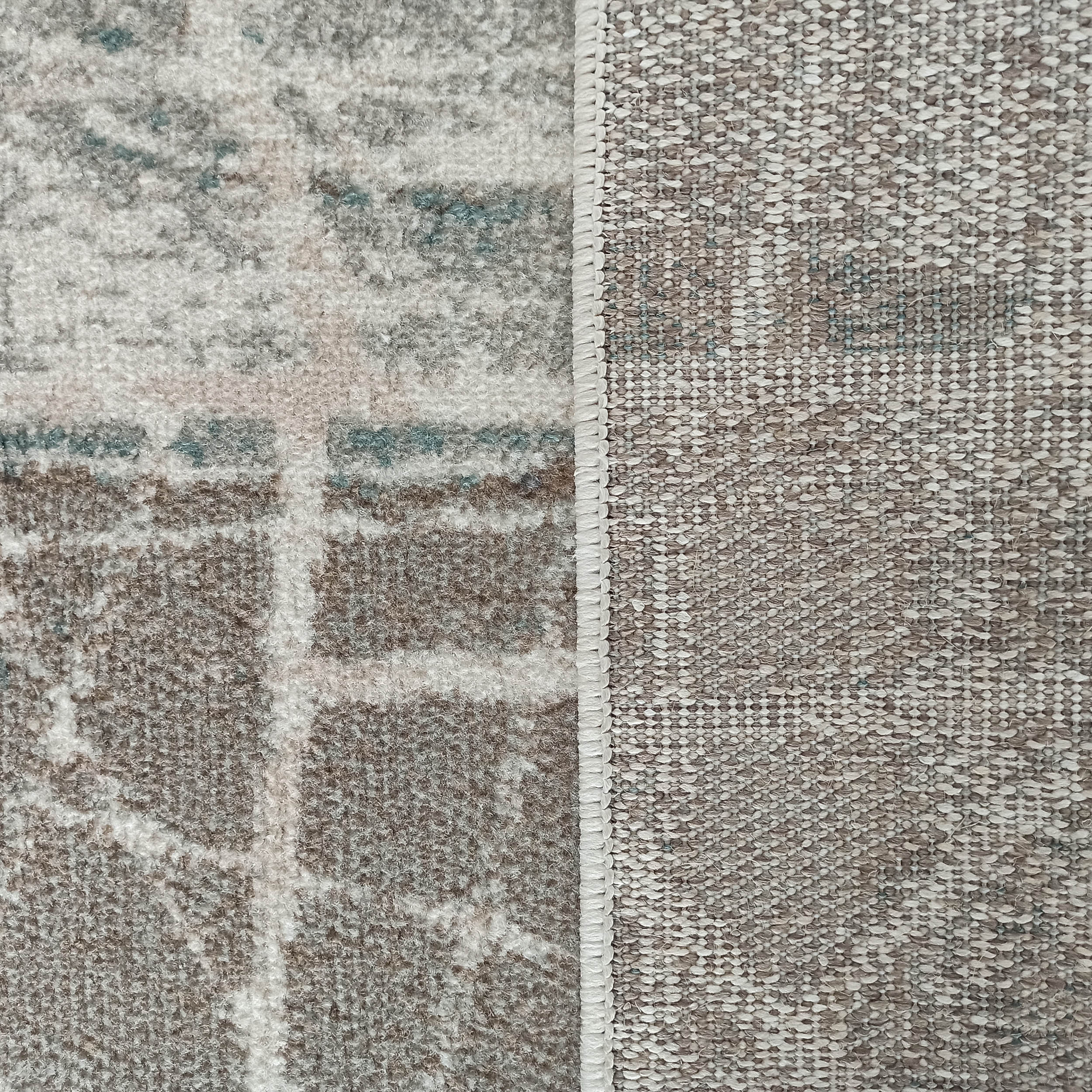 Tapis dont le dessus doux et texturé présente des motifs abstraits gris, blancs et bleus. Son envers est beige et tissé