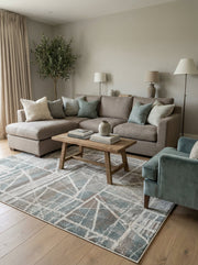 Tapis rectangulaire à motifs géométriques abstraits bleus, gris, marron et blanc cassé sur un parquet de salon