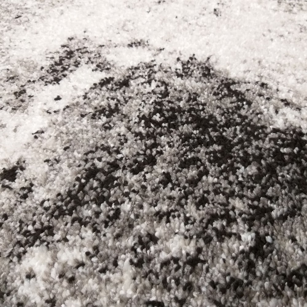 Tapis à poils longs blanc, gris et noir, avec un motif abstrait tacheté rappelant des éclaboussures d'encre