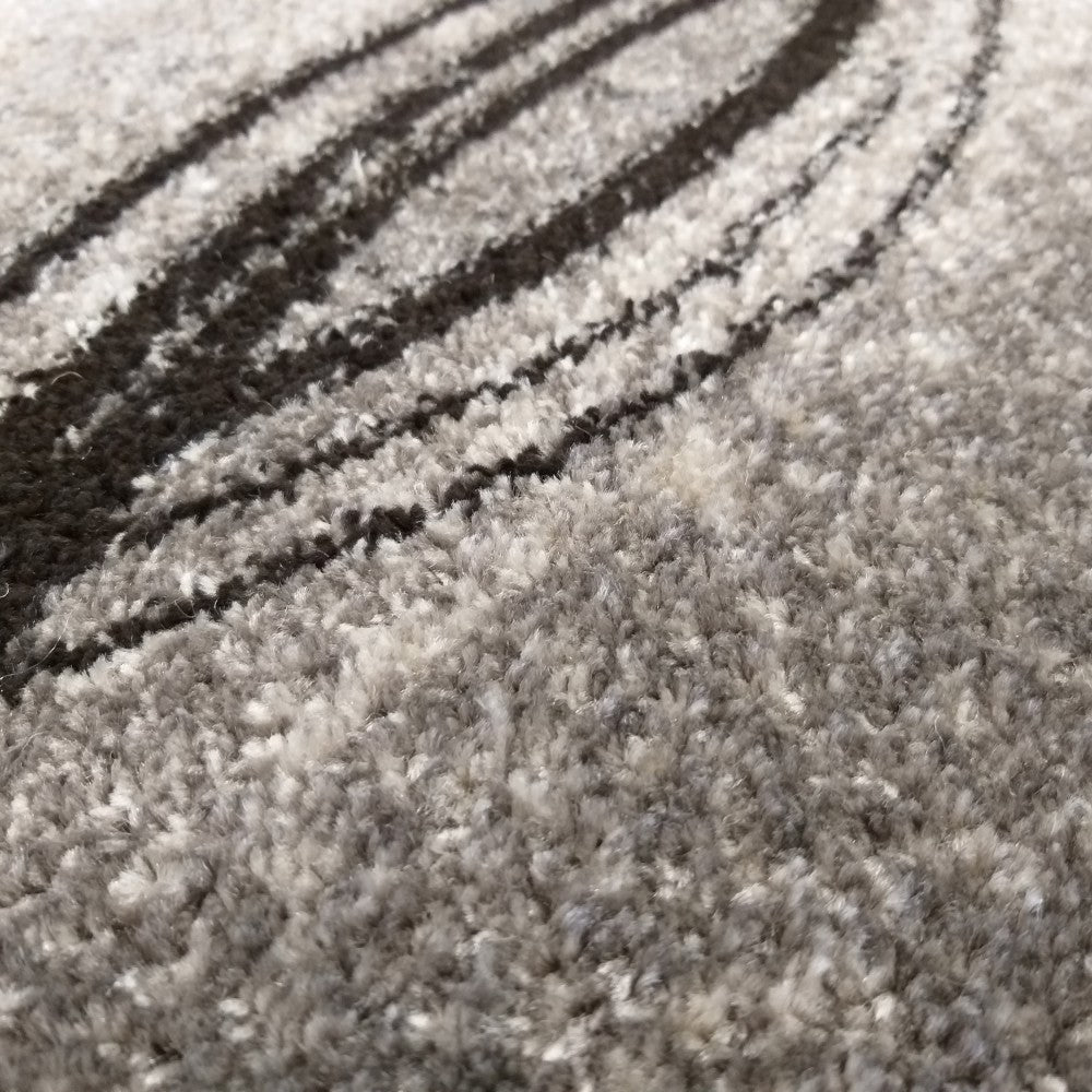 Gros plan d'un tapis gris à poils longs, orné de motifs abstraits sombres et ondulés