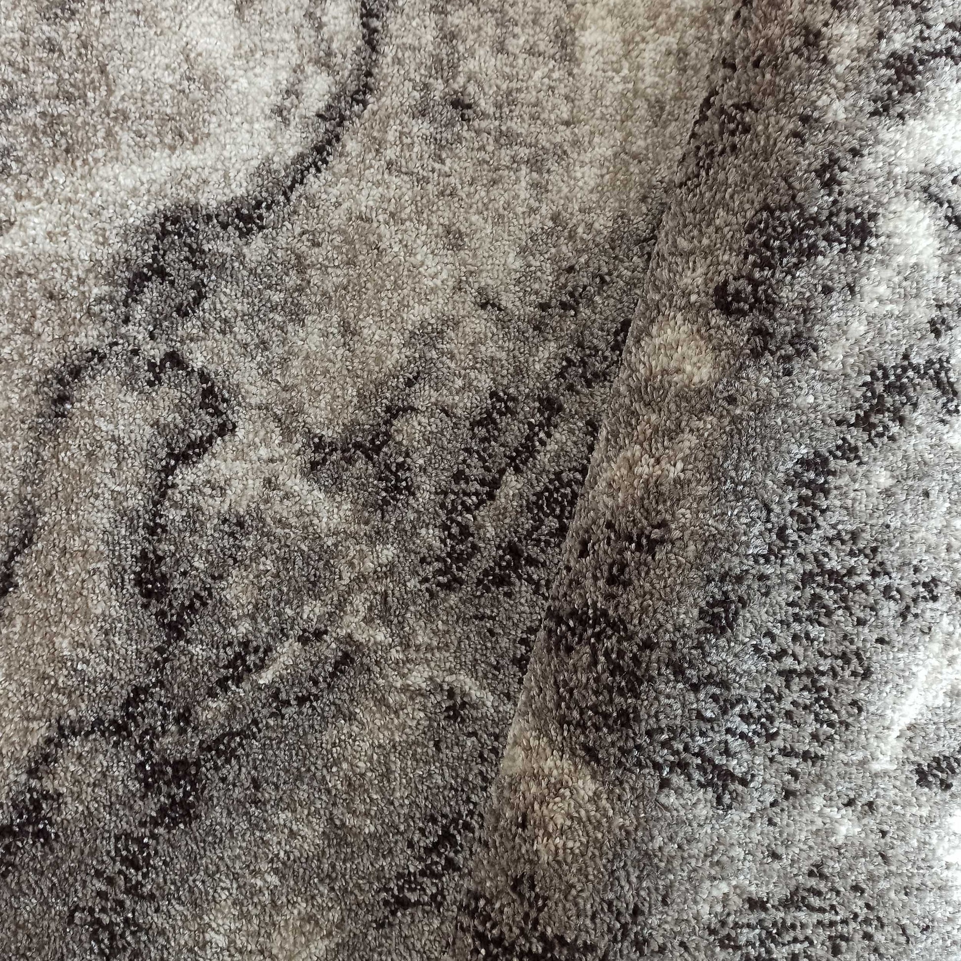 Tapis moelleux aux motifs abstraits et marbrés, dans des teintes de gris clair et foncé, avec une texture douce