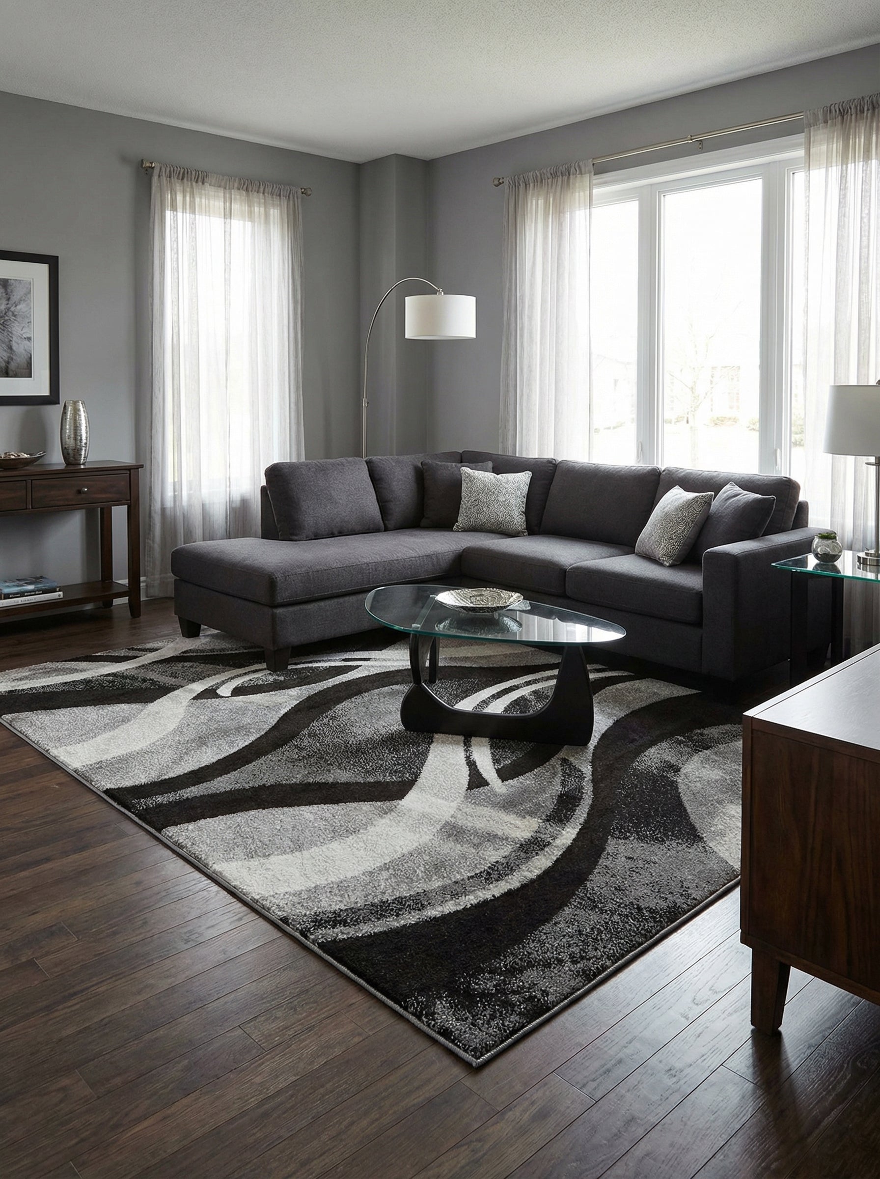 Tapis rectangulaire aux motifs abstraits de vagues noires, grises et blanches, posé sur un parquet foncé dans un salon moderne