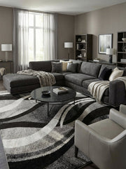 Tapis rectangulaire texturé aux motifs abstraits de vagues noires, grises et blanches dans un salon moderne