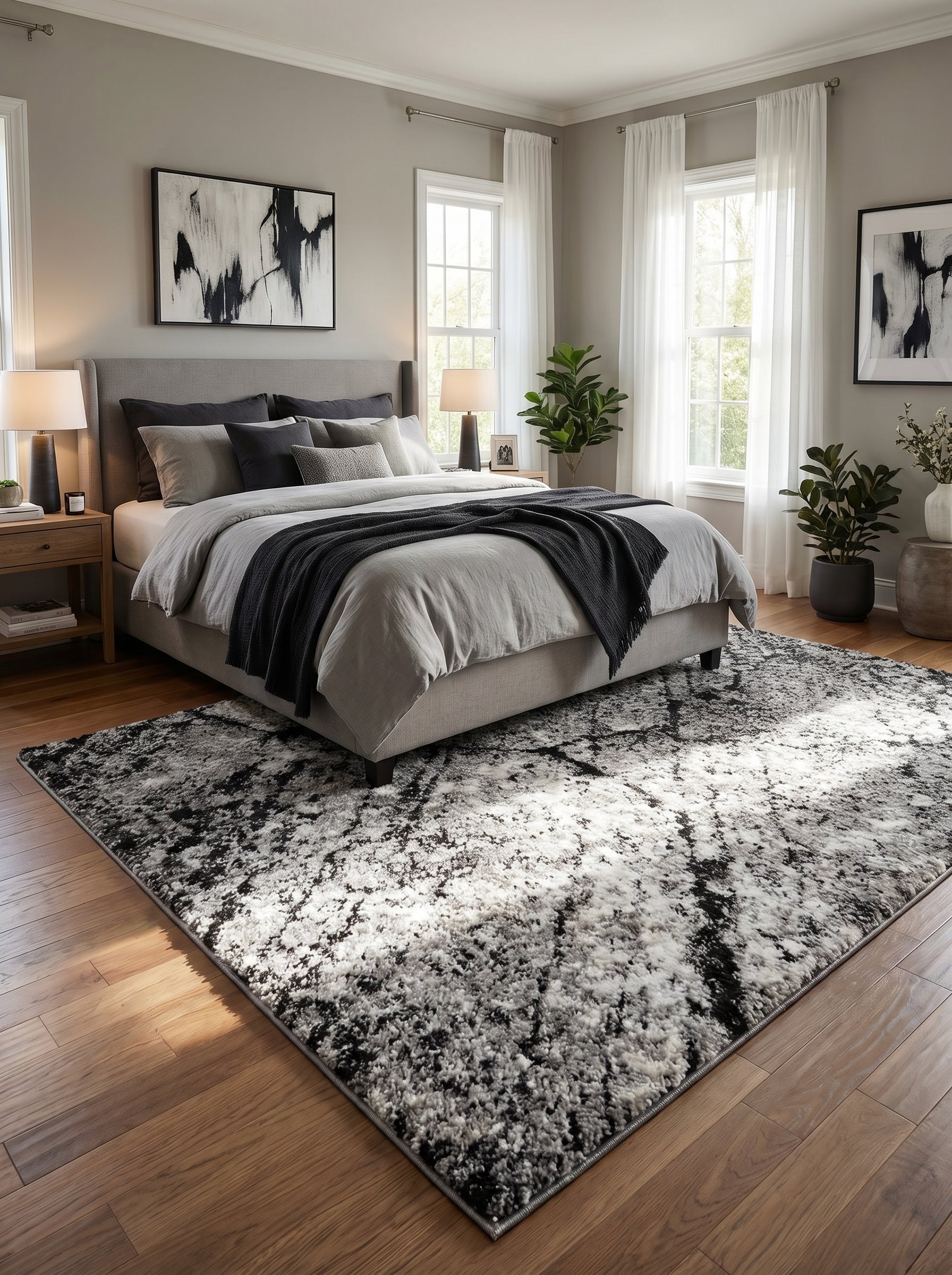Tapis rectangulaire aux motifs abstraits et texturés, mêlant le noir, le blanc et diverses nuances de gris, dans une chambre