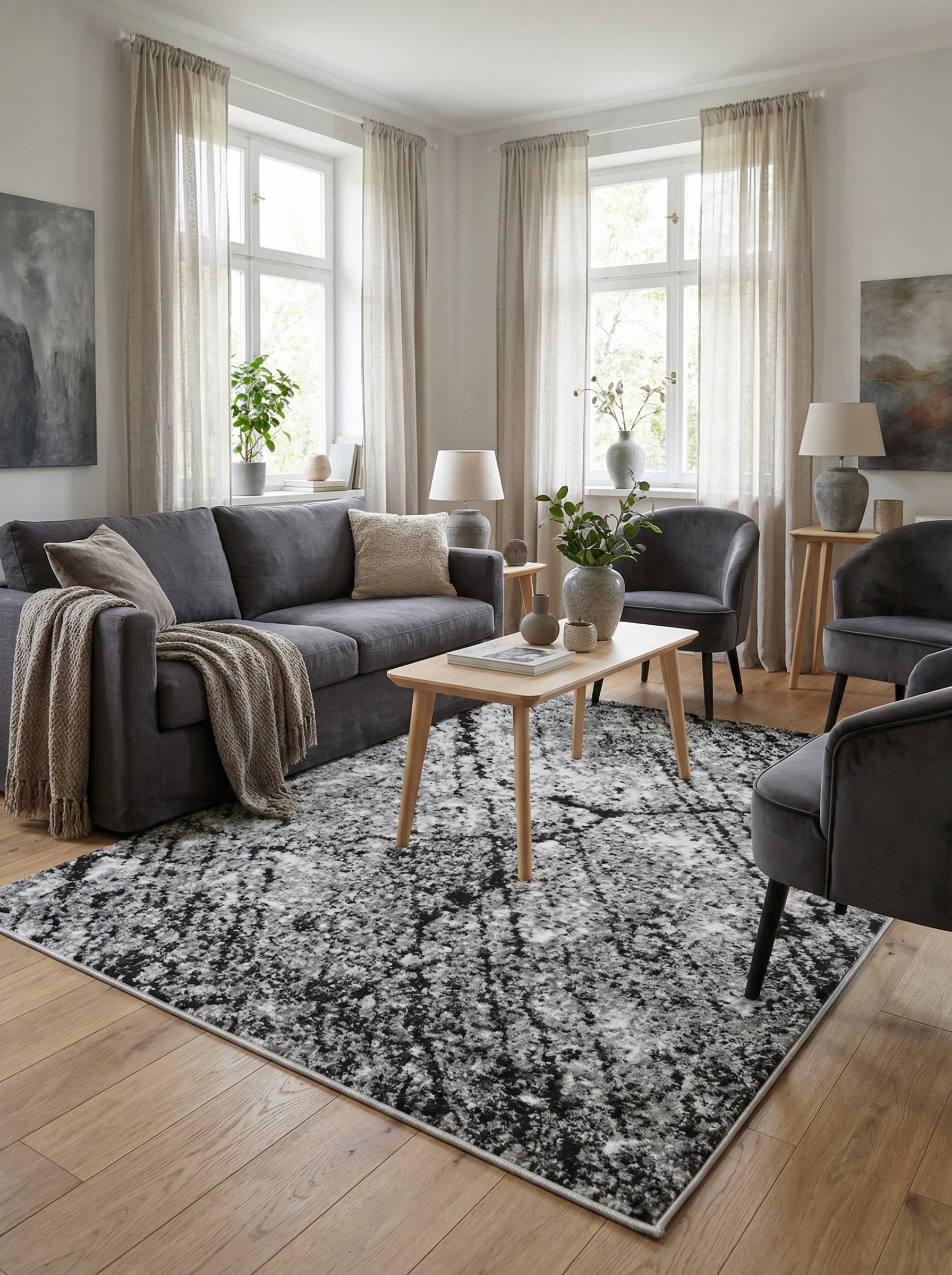 Tapis rectangulaire aux motifs abstraits et tachetés noirs, gris et blancs, posé sur un parquet clair dans un salon moderne